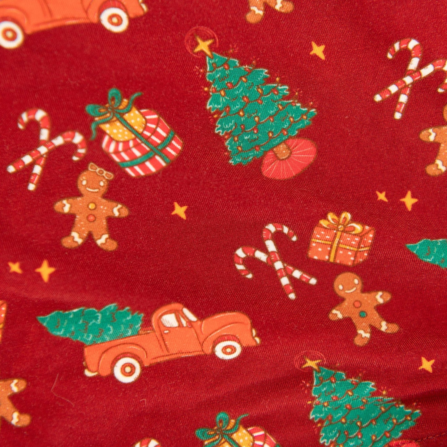 A close-up of a red bamboo PJ set, showing a festive holiday print including gingerbread men, candy canes, and Christmas trees.