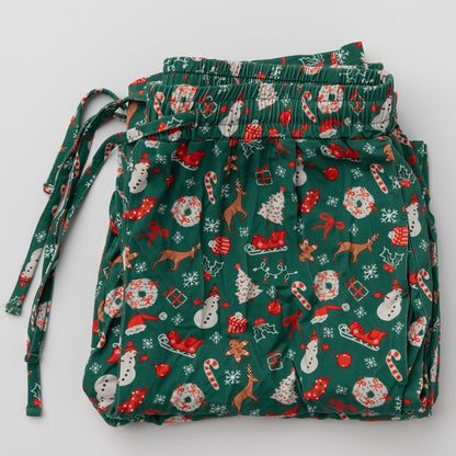 A flat lay of the folded Apostle Living Inc. green Christmas pajama pants with a festive pattern of snowmen, reindeer, and candy canes.