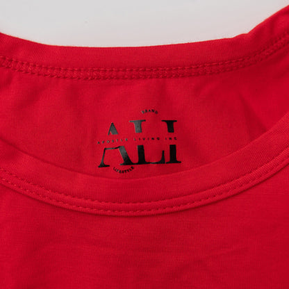 A close-up detail shot of the black Apostle Living Inc. brand tag on the collar of a red men's Christmas pajama shirt.