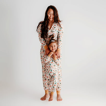 A mother and daughter wearing matching soft bamboo Christmas pajamas, both smiling and holding hands.